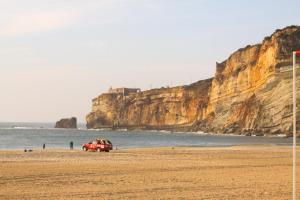 a car parked on a beach next to the ocean at FerhouseDreams-Praia in Nazaré