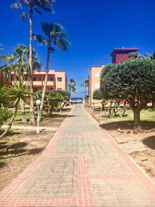 a brick pathway with palm trees and a building at Fuerteventura - La Caleta, Parques Holandes in La Oliva