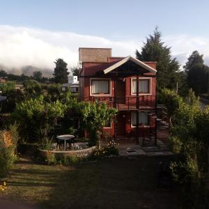 una casa roja con una mesa delante en Cabañas La Maria Lourdes en Tafí del Valle