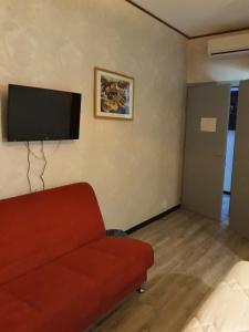 uma sala de estar com um sofá vermelho e uma televisão de ecrã plano em Sira House Milano em Milão