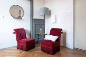 - deux chaises rouges et une table avec un miroir dans l'établissement 1834 Colmar, à Colmar