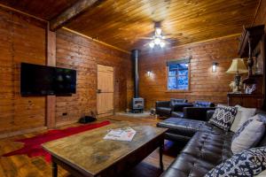 a living room with leather furniture and a flat screen tv at Blaxland's Cottage in Broke
