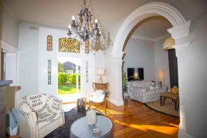 a living room with white furniture and a chandelier at Camellia Cottage in Cessnock