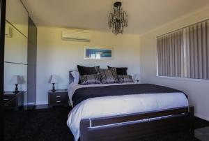 a bedroom with a large bed and a chandelier at Harmans Lodge Private Rural Escape in Wilyabrup