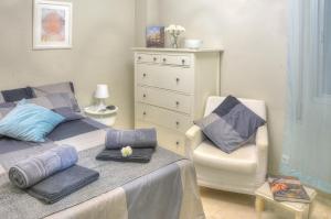 - une chambre avec un lit, une chaise et une commode dans l'établissement APARTAMENTO MURILLO EN EL PRADO, à Séville