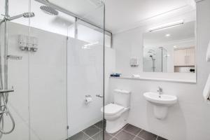 a white bathroom with a toilet and a sink at Tangalooma Island Resort in Tangalooma