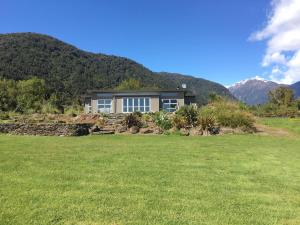 a house in a field with mountains in the background at Franz Josef Villa in Franz Josef