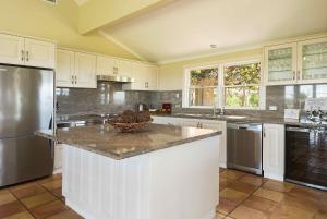 cocina con armarios blancos y encimera de granito en Holman Estate en Pokolbin
