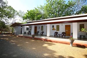 a white building with chairs and tables on it at Amadi Rest in Kataragama