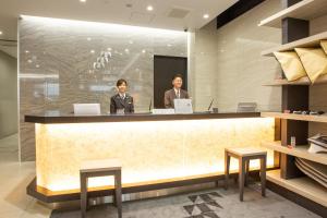 two people standing at a counter in a lobby at Kuretake Inn Osaka Midousuji Hommachi in Osaka +94 photos