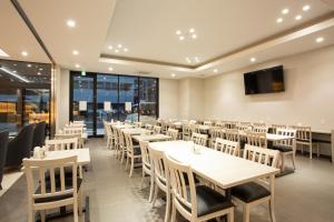 a restaurant with tables and chairs and a flat screen tv at Kuretake Inn Osaka Midousuji Hommachi in Osaka