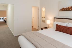 um quarto branco com uma grande cama branca e um candeeiro em Boulcott Suites em Wellington