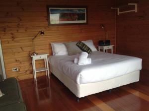 a bedroom with a white bed with two tables at Milbrodale Lodge in Broke