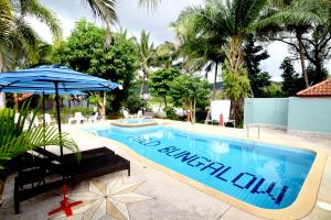 a swimming pool with an umbrella and a chair next to it at Mild Garden View Resort in Ao Nang Beach