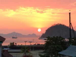 una puesta de sol sobre un cuerpo de agua con una montaña en Bajo Nature Backpackers, en Labuan Bajo