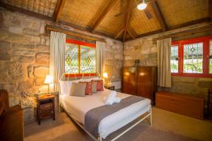 1 dormitorio con cama y pared de piedra en Monkey Place Country House, en Broke