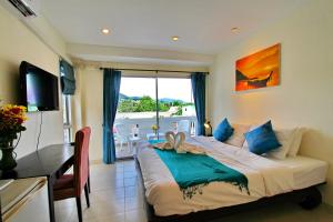 a bedroom with a bed and a table and a window at The Green House in Kata Beach