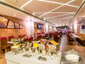a restaurant with white tables and red chairs at Hotel Rockdale in Visakhapatnam