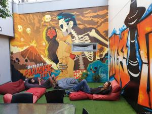 three people laying on bean bags in front of a mural at Metro Adventurer Backpackers in Auckland