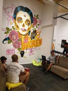 un grupo de personas sentadas en una habitación con un gran mural en Metro Adventurer Backpackers en Auckland
