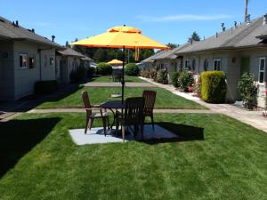 a table with a umbrella and chairs in a grassy area at Milwaukie Inn Portland South in Milwaukie