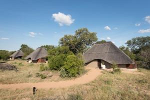 a group of huts with thatched roofs in a field at Kambaku River Sands in Timbavati Game Reserve