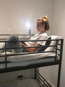 une femme assise au-dessus d'un lit superposé dans l'établissement The Mornington Camden Female only Hostel, à Londres