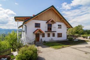 ein weißes Haus mit einem Holzdach in der Unterkunft Ferienwohnung Traumaussicht in Leutschach