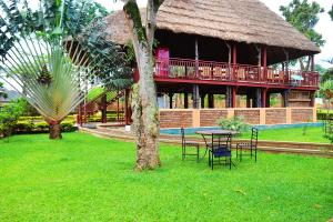 a building with a table and chairs in the grass at Eco Resort Kasenyi in Entebbe