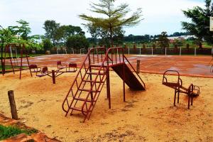 an empty playground with a slide in the dirt at Eco Resort Kasenyi in Entebbe