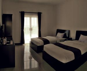 una camera d'albergo con due letti e una finestra di Amaranta Guest House a Batu