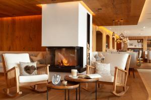 een open haard in een woonkamer met stoelen en een tafel bij Hotel Seevilla Wolfgangsee in St. Wolfgang