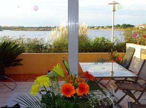 - une table et des chaises sur une terrasse avec vue sur l'eau dans l'établissement Les rives du lac, au Grau-du-Roi