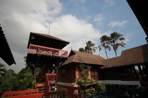 a building with a balcony and a house with palm trees at Carpe Diem Orchard Home in Rawang