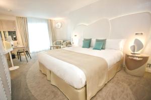 une chambre d'hôtel avec un grand lit blanc avec des oreillers bleus dans l'établissement Miramar La Cigale Hotel Thalasso & Spa, à Arzon 42 autres photos
