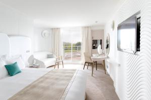 a white bedroom with a bed and a living room at Miramar La Cigale Hotel Thalasso & Spa in Arzon +45 photos