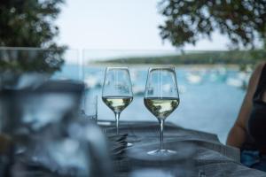 two glasses of white wine sitting on top of a table at Mon Perin Castrum - Rooms Dado in Bale