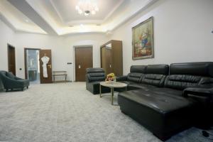 a living room with a black leather couch and chairs at Parliament Palace Hotel in Khujand