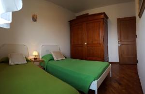 una camera con 2 letti verdi e un armadio in legno di Casa Leonardo a Quarrata