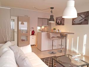 ハイリゲンハーフェンにあるLomaのリビングルーム(白いソファ付)、キッチンが備わります。