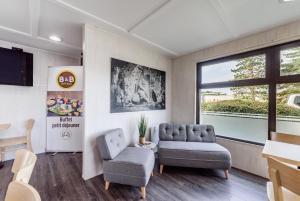 a living room with a couch and a chair at B&B HOTEL Belfort Bessoncourt in Belfort