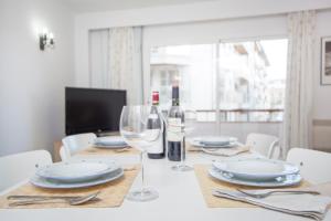 a dining table with glasses and plates and a bottle of wine at Curling in Port d'Alcudia