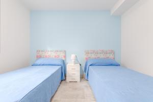 two beds in a white room with blue sheets at Bon Estar in Port d'Alcudia