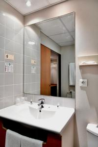 La salle de bains est pourvue d'un lavabo et d'un grand miroir. dans l'établissement In Situ Hotel, à Valenciennes