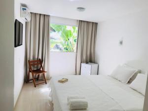 a bedroom with a bed with a chair and a window at Vila do Morro Pousada in Morro de São Paulo