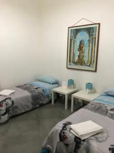 ナポリにあるCasa Nanàのベッド2台が備わる客室で、壁には絵画が飾られています。