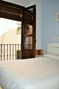 sypialnia z białym łóżkiem i oknem w obiekcie Pension Castil w Grenadzie