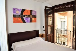 Un dormitorio con una cama y un cuadro en la pared. en Pension Castil, en Granada
