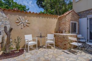 a patio with chairs and a table and a brick wall at Mediterranes Ferienhaus m. Terrasse in Veli Lošinj