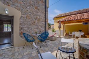 un patio con sedie e tavoli e un edificio di Mediterranes Ferienhaus m. Terrasse a Veli Lošinj (Lussingrande)